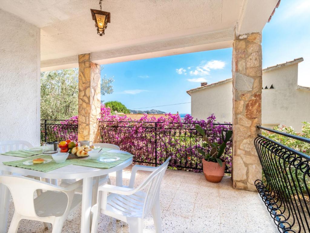 una mesa blanca y sillas en un patio con flores púrpuras en Holiday Home People I by Interhome, en Roses