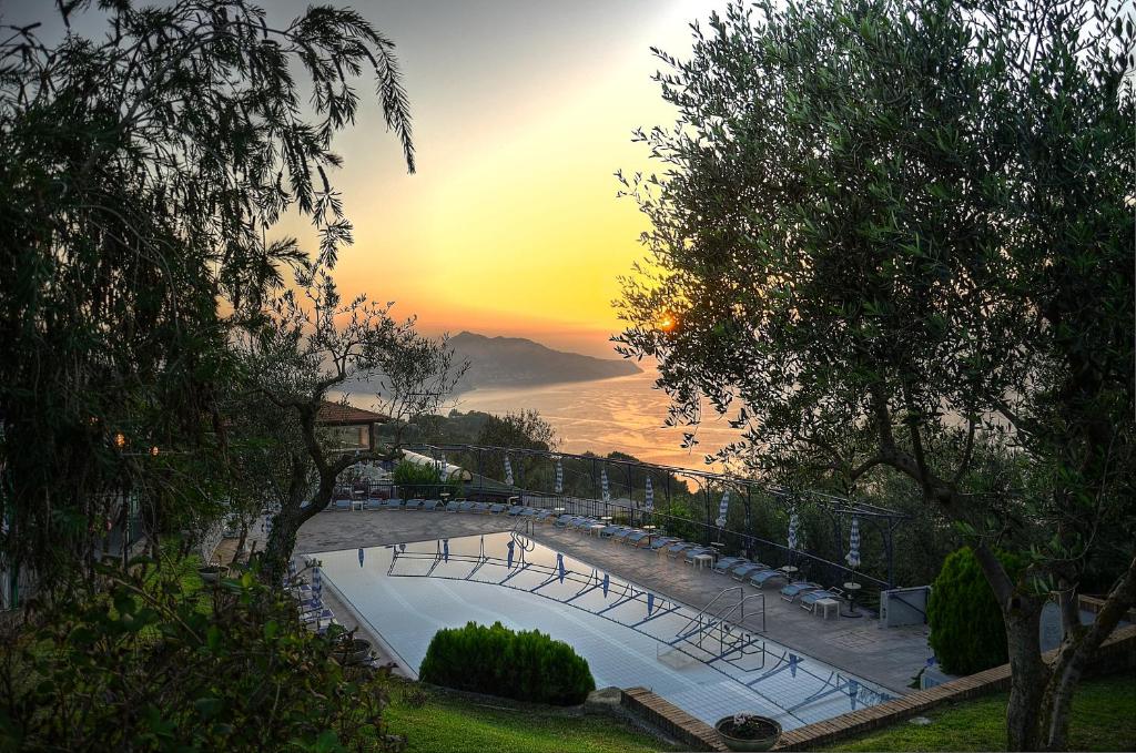 a swimming pool with a sunset in the background at Gocce Di Capri Resort in Massa Lubrense