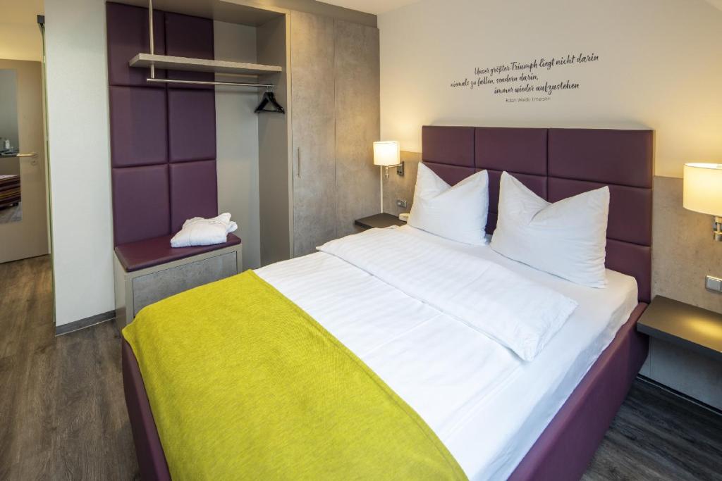 a bedroom with a large white bed with a yellow blanket at Hotel Gloria Superior in Stuttgart