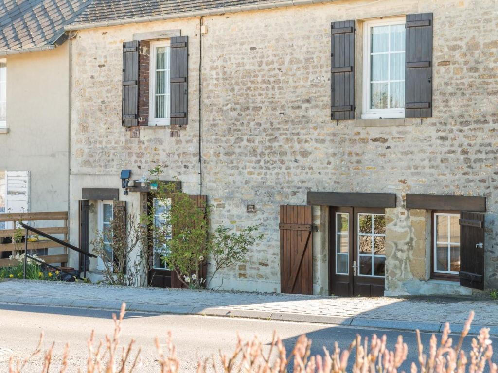 - un bâtiment en briques avec des portes et des fenêtres noires dans l'établissement Simplistic holiday home with terrace, à Saint-Laurent-sur-Mer