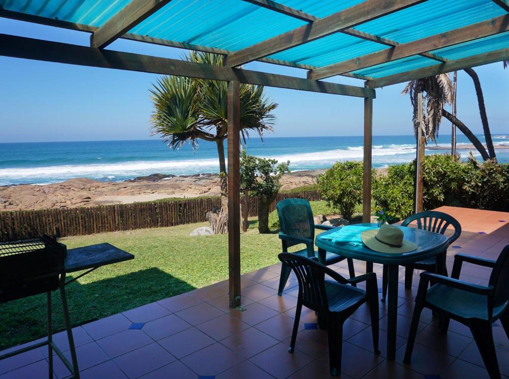 un patio con mesa, sillas y el océano en Southern Comfort - Starfish en Margate