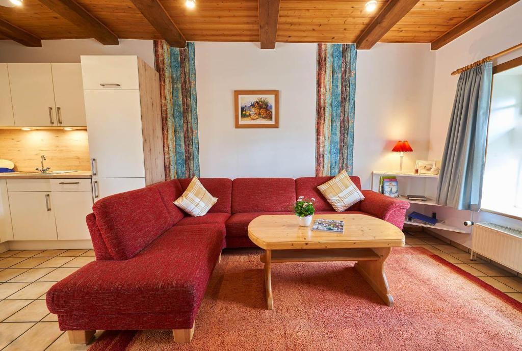 een woonkamer met een rode bank en een tafel bij Ferienhof-Heidemann in Neustadt am Rübenberge
