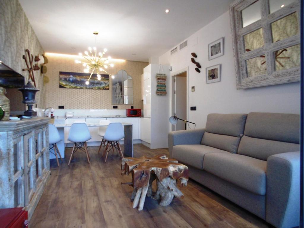 トレモリノスにあるApartamentos LOLA y MANUELA en primera línea playa Carihuela con excelente Terraza-jardin de 80 m2 frente al Mar con aparcamiento privado Ideal para descansar oyendo las olas del Marのソファとテーブルとキッチンのあるリビングルーム