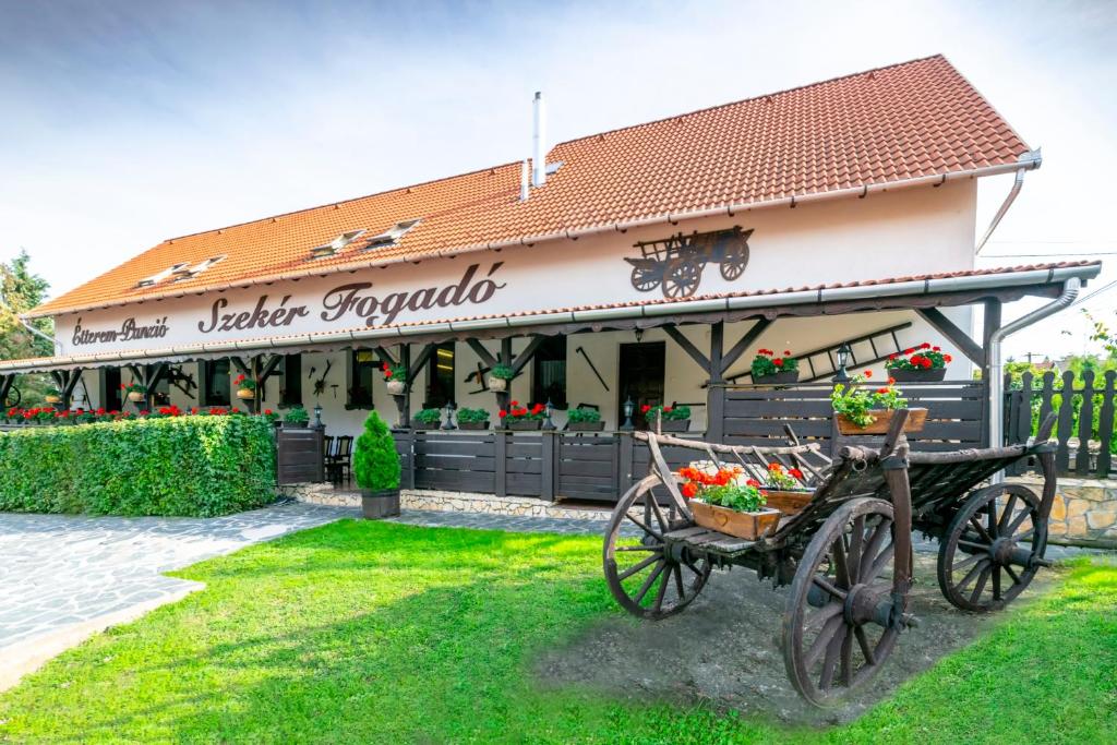 a building with a cart with flowers in it at Szekér Fogadó in Bátonyterenye