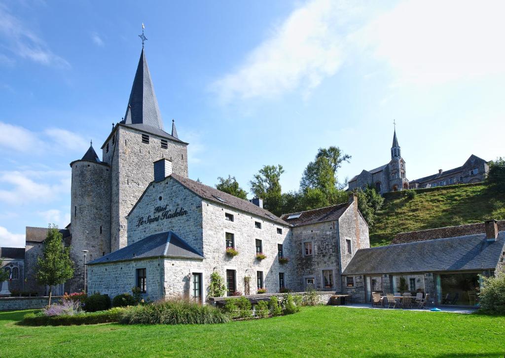 un ancien bâtiment en pierre avec une église sur une colline dans l'établissement Hotel Le Saint Hadelin, à Celles