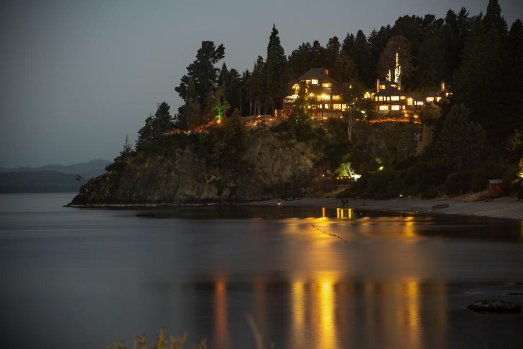 a house on an island in the water at night at Charming Luxury Lodge & Private Spa in San Carlos de Bariloche