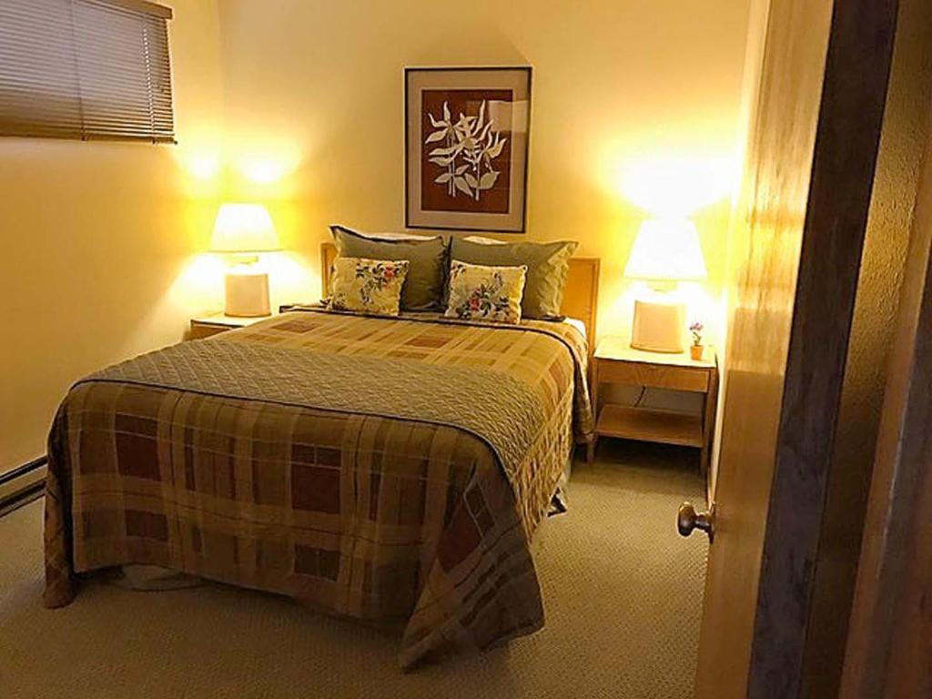 a bedroom with a bed and two lamps on two tables at Jackson Hole Vacation Condominiums, a VRI resort in Wilson