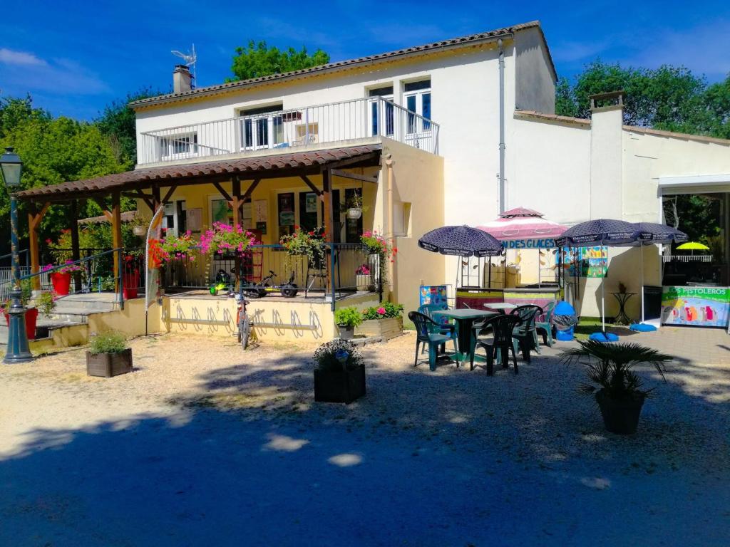a house with a patio with tables and umbrellas at Camping en Ardeche Le Lion in Bourg-Saint-Andéol