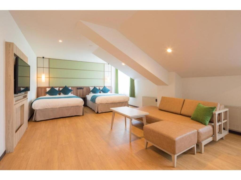 ein Wohnzimmer mit zwei Betten und einer Couch in der Unterkunft Tazawako Lake Resort & Onsen / Vacation STAY 78934 in Senboku
