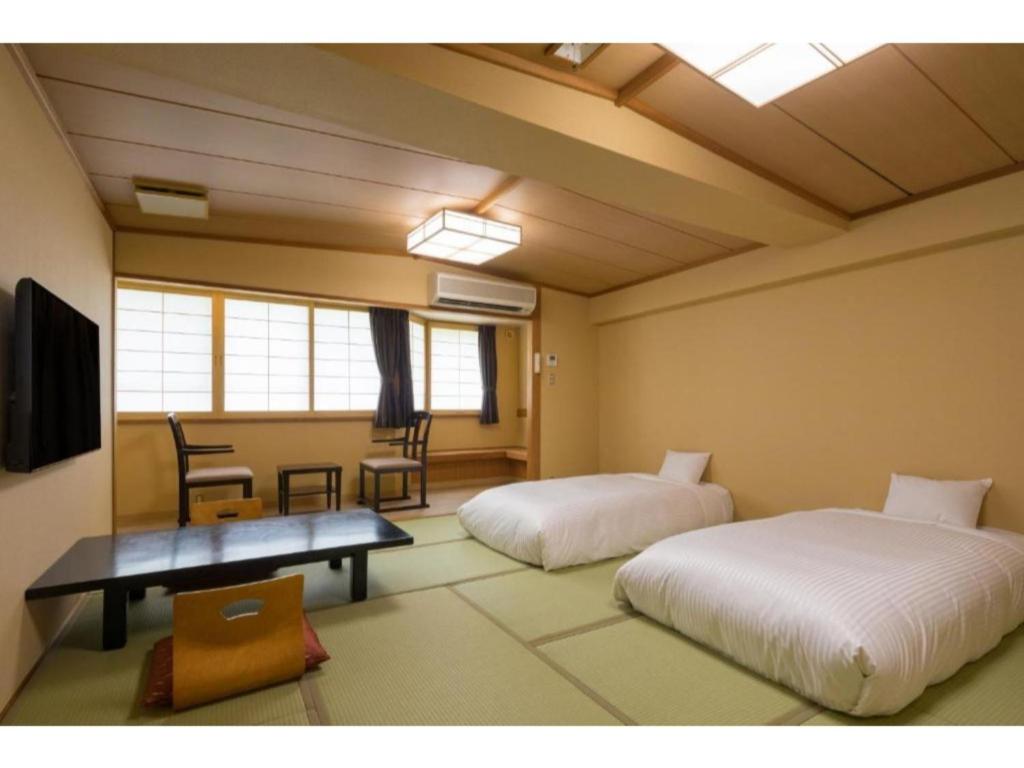 um quarto com duas camas e uma mesa e cadeiras em Tazawako Lake Resort & Onsen / Vacation STAY 78936 em Senboku