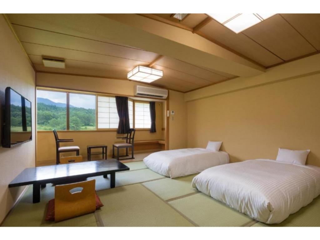 sypialnia z 2 łóżkami, stołem i krzesłami w obiekcie Tazawako Lake Resort & Onsen / Vacation STAY 78984 w mieście Senboku