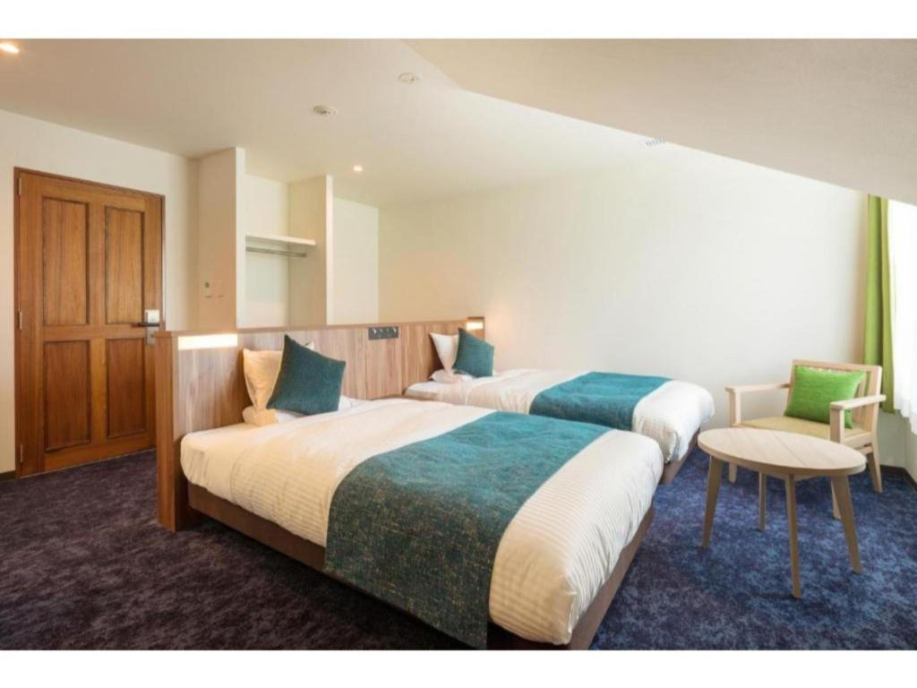 a hotel room with two beds and a chair at Tazawako Lake Resort & Onsen / Vacation STAY 78931 in Senboku