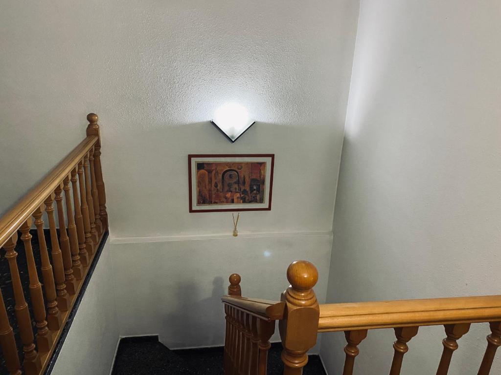 un couloir avec un escalier avec une photo sur le mur dans l'établissement Habitaciones dakar, à Rubí