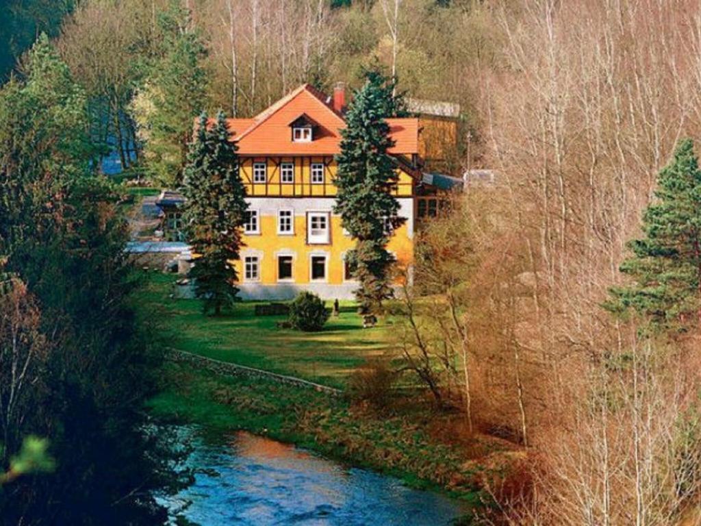 una casa grande con techo naranja junto a un río en Apartment in a villa with park in Gro schirma, en Großschirma