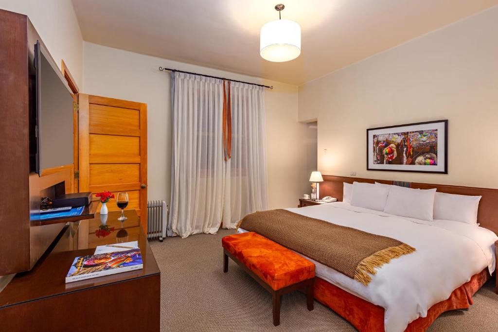a bedroom with a large bed and a television at LP Los Portales Hotel Tarma in Tarma