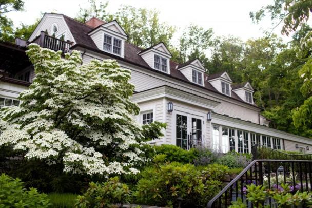 a white house with a flowering tree in front of it at Bedford Post Inn in Bedford