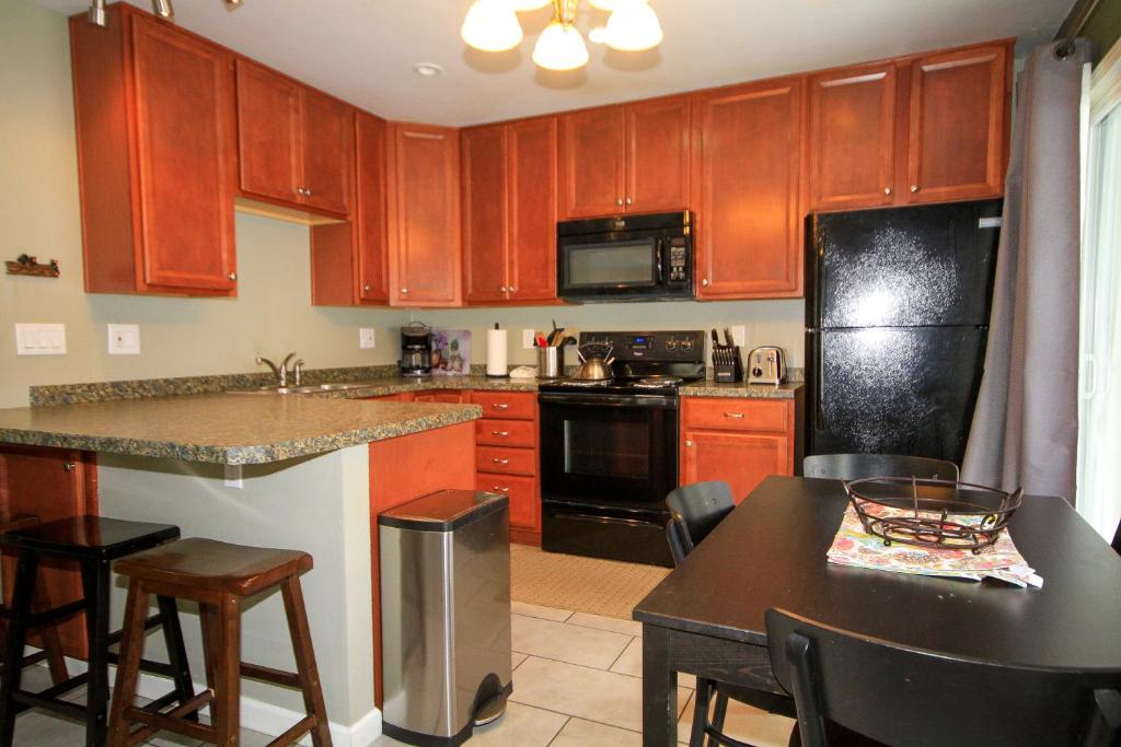 a kitchen with wooden cabinets and a black refrigerator at Sierra Park Villas #65 in Mammoth Lakes