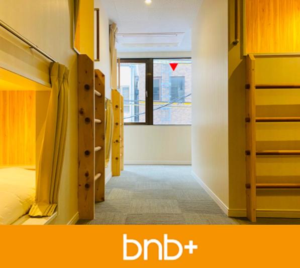 Schlafsaal mit Etagenbetten und Fenster in der Unterkunft bnb+ Shinsaibashi in Osaka
