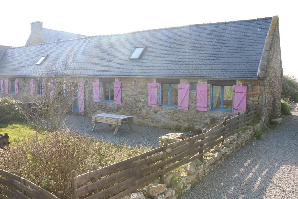 a stone house with pink shutters and a bench in front at Les Gîtes Aux Volets Roses in Landunvez