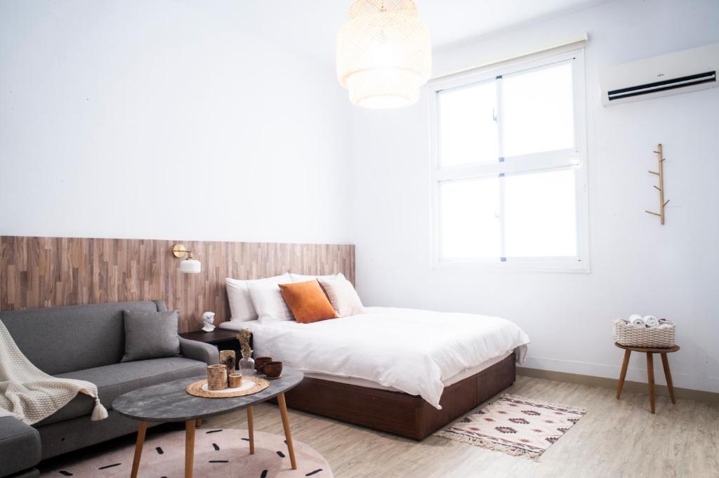 een slaapkamer met een bed, een bank en een raam bij MH Alley in Tainan