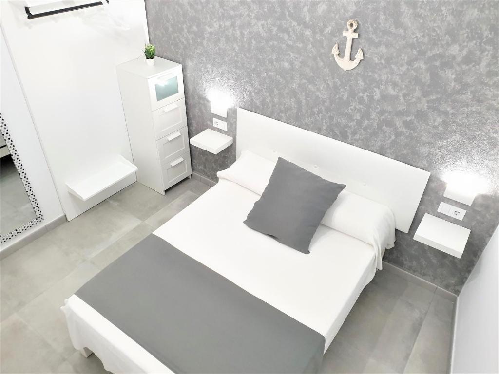 Un pequeño dormitorio con una cama blanca y un ancla en la pared en Apartament Fora Port, en Fornells