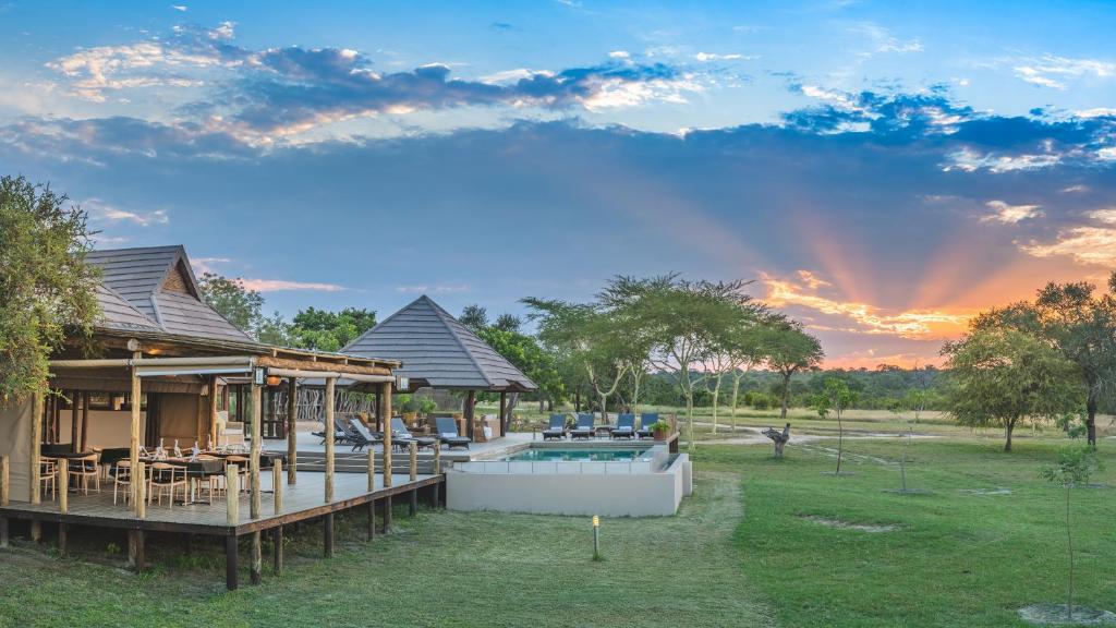 a house with a pool in a yard with a sunset at Nkorho Bush Lodge in Sabi Sand Game Reserve