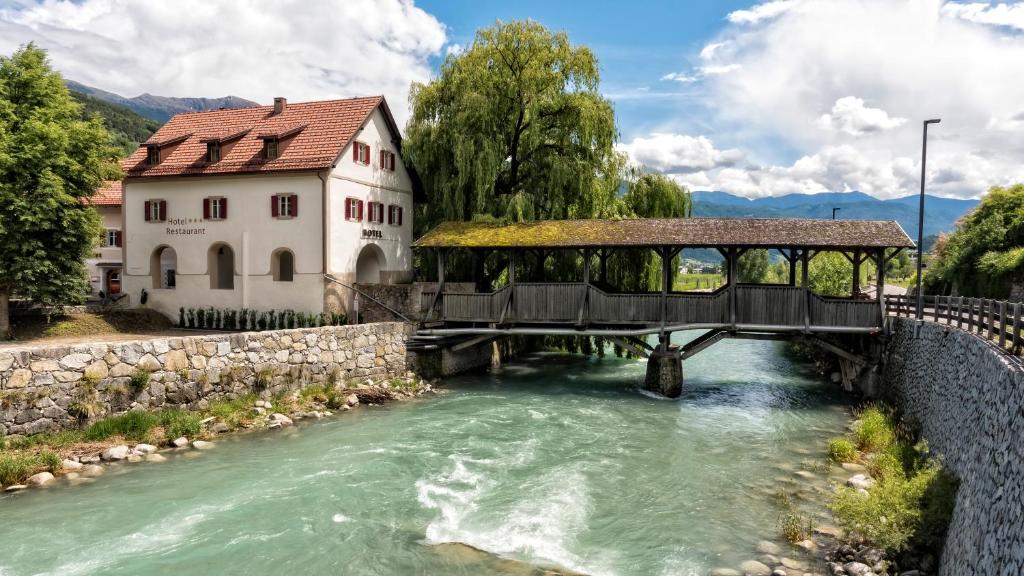 a bridge over a river in front of a building at Hotel Brückenwirt in Novacella