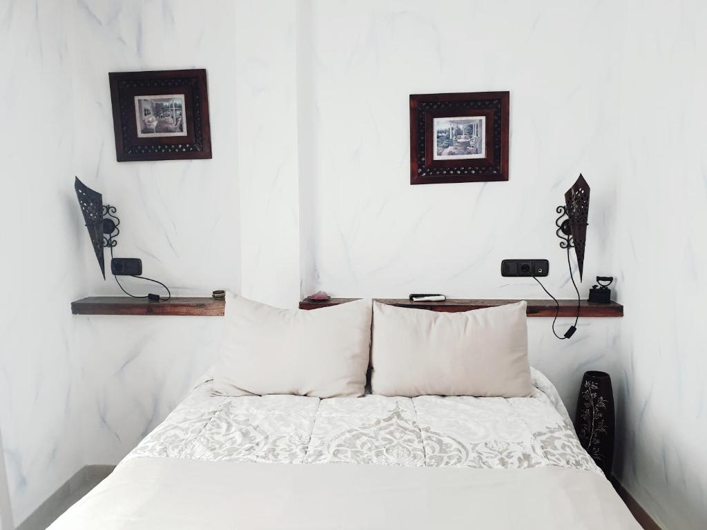 1 dormitorio con 1 cama con sábanas y almohadas blancas en Hospedería El Caravansar en Frigiliana