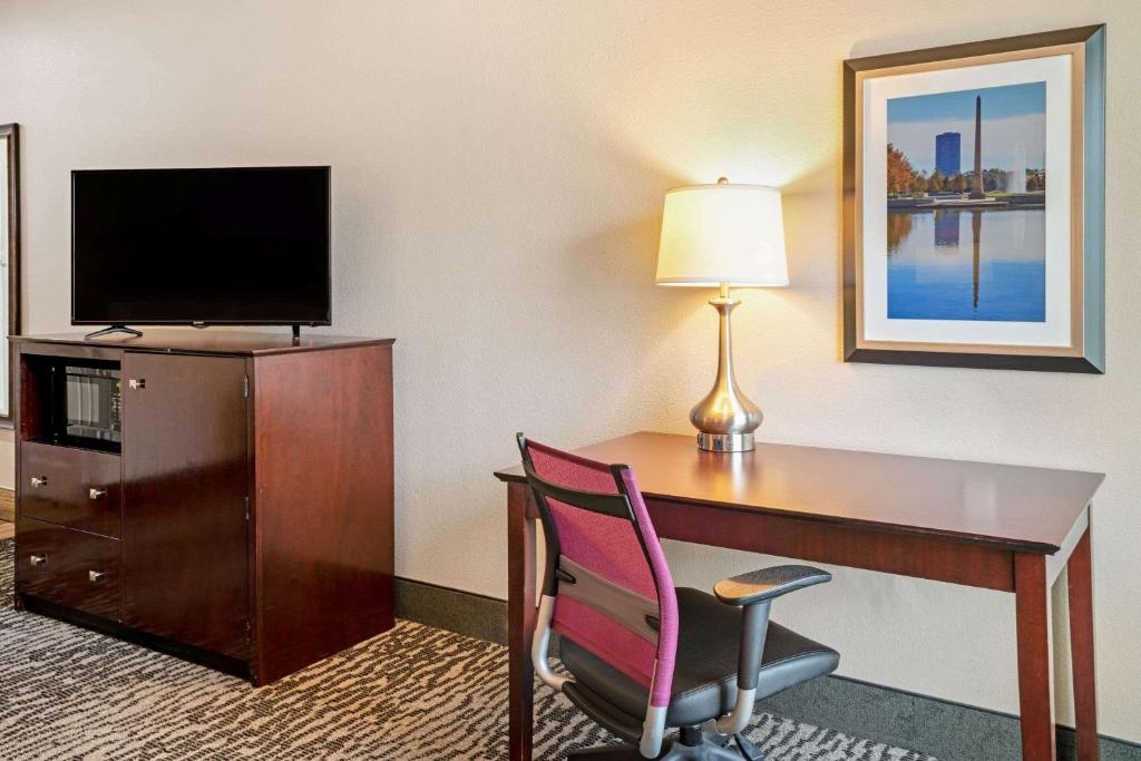 a hotel room with a desk with a chair and a television at La Quinta by Wyndham Houston - Magnolia in The Woodlands