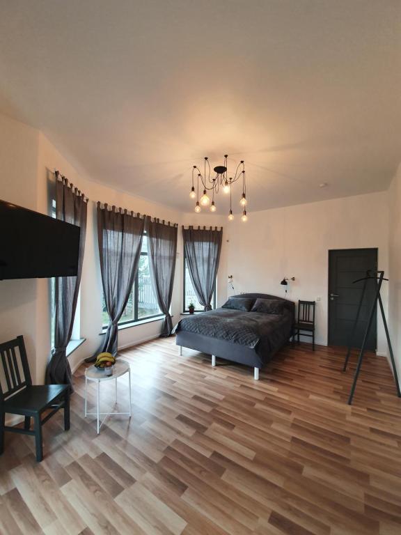 1 dormitorio con 1 cama y suelo de madera en Valet Apartment en Mārupe