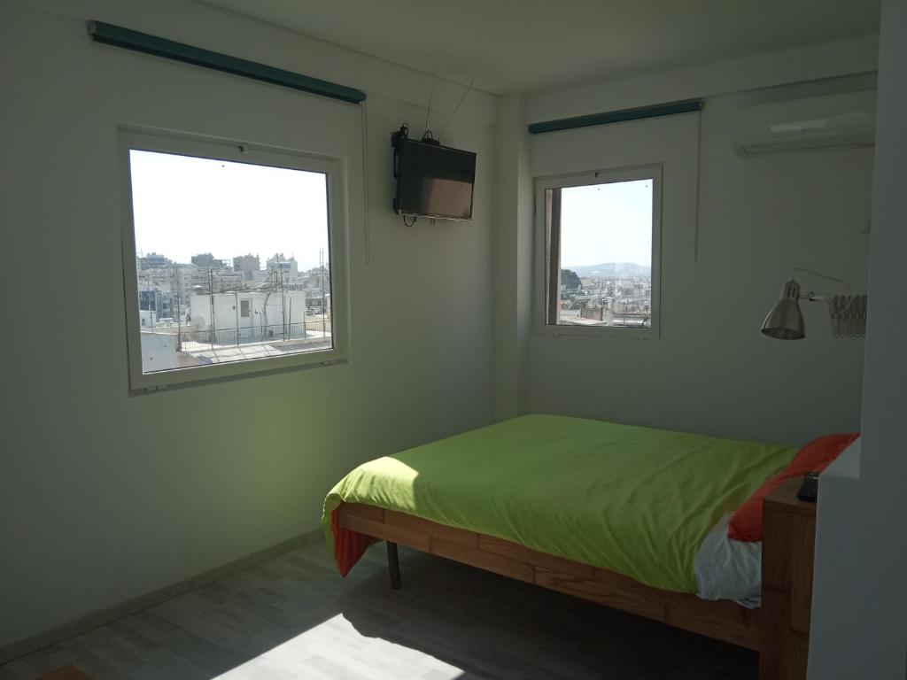 sypialnia z łóżkiem i 2 oknami w obiekcie Roof Top Studio in Koukaki w Atenach
