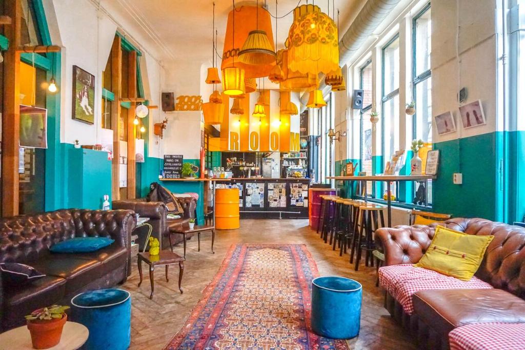 a room with couches and chairs and a bar at Hostel ROOM Rotterdam in Rotterdam