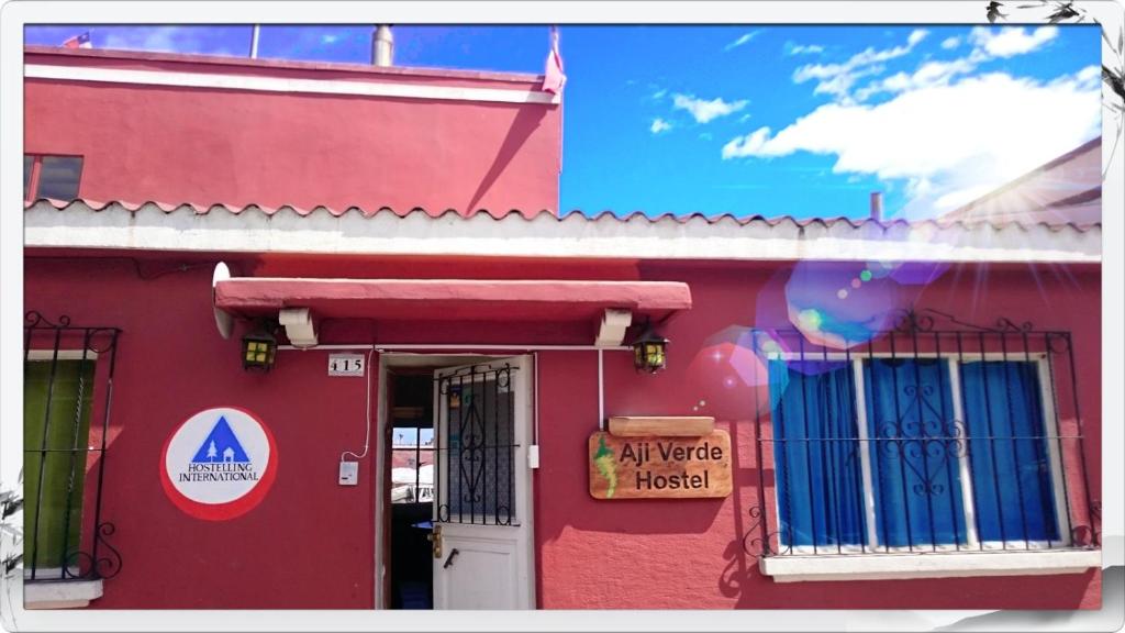 a red building with a sign on the side of it at Aji Verde Hostel in La Serena