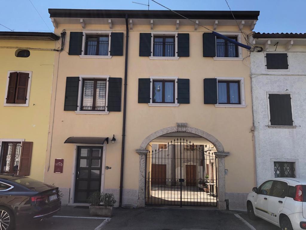 ein Gebäude mit einem Tor und Autos auf einem Parkplatz in der Unterkunft La casa della Ada in Castelnuovo del Garda
