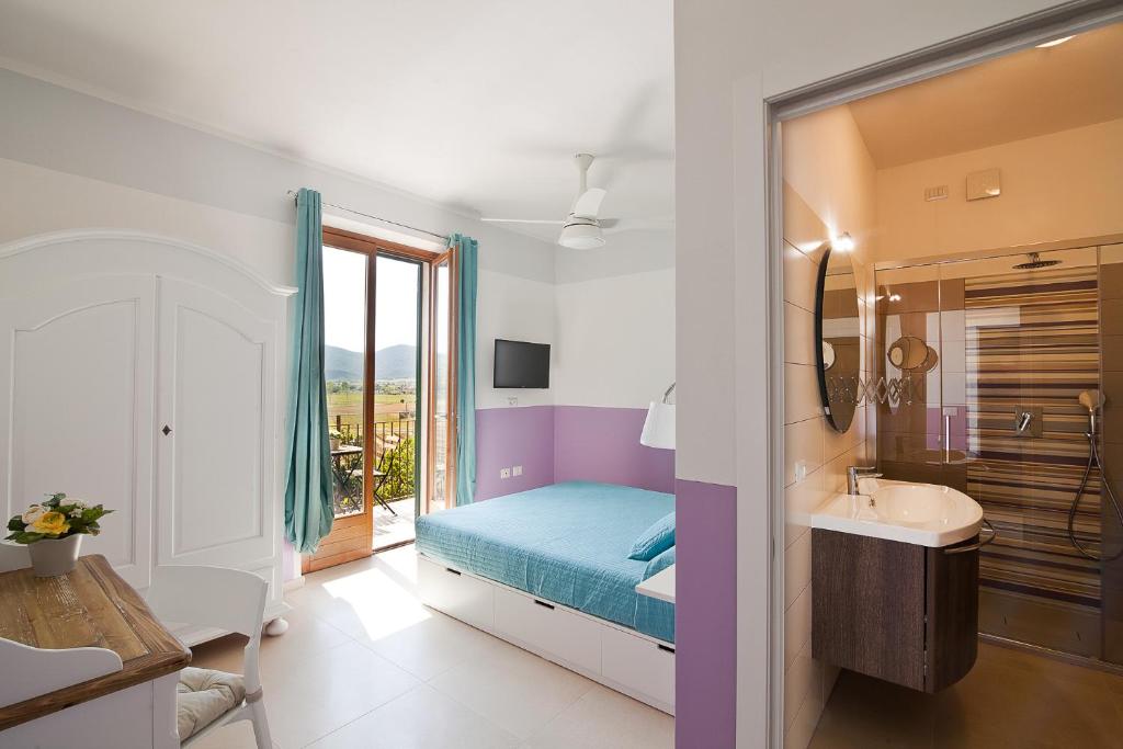 a bedroom with a bed and a sink and a mirror at Poggiolivi Agriturismo Bio in Maremma in Alberese