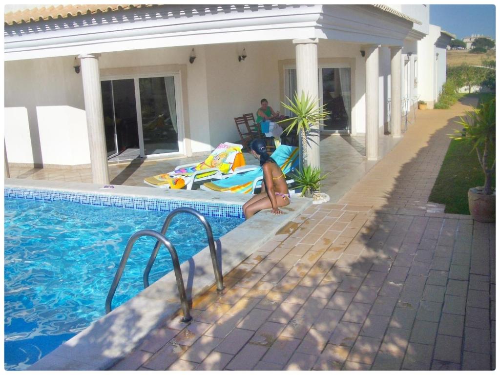 a woman laying on a surfboard next to a swimming pool at Casa do Mar in Albufeira