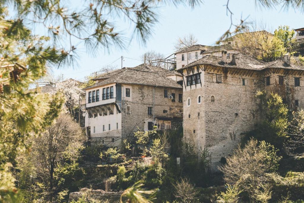 um antigo edifício de pedra numa colina com árvores em Braja House em Gjirokastër