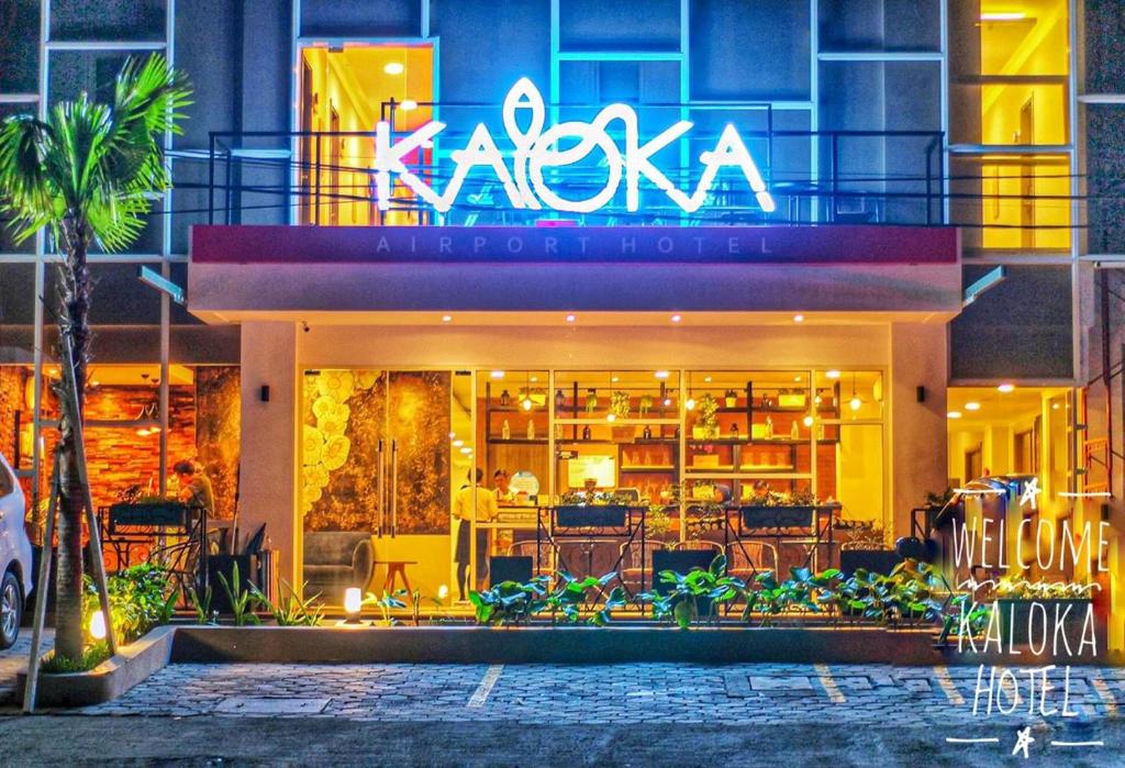 ein Restaurant mit Neonschild an der Seite eines Gebäudes in der Unterkunft Kaloka Airport Hotel in Labu Sumbawa