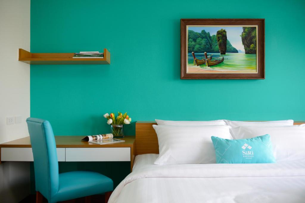 1 dormitorio con pared azul, cama y escritorio en SiRi Ratchada Bangkok en Bangkok