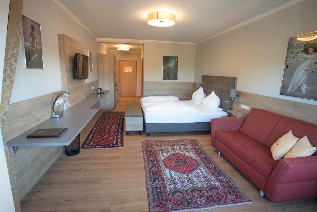 ein Hotelzimmer mit einem Bett und einem roten Sofa in der Unterkunft Der Marienhof Hotel Garni in Graz