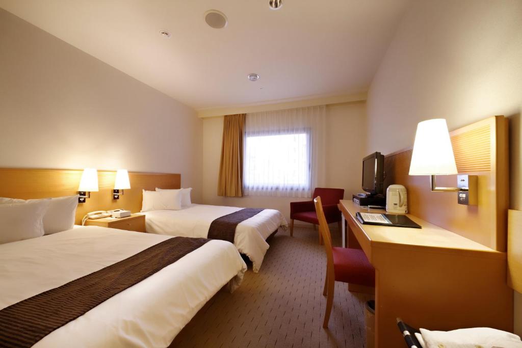 um quarto de hotel com duas camas e uma televisão em Welco Narita em Narita