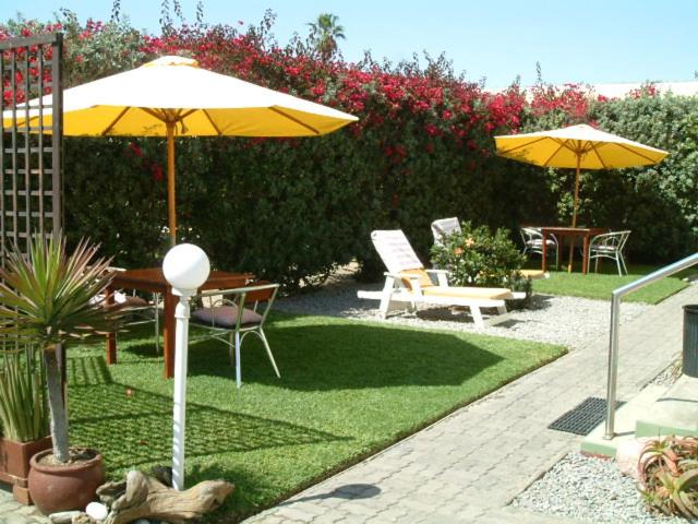 eine Terrasse mit Sonnenschirmen, Stühlen und Tischen in der Unterkunft Pension d'Avignon in Swakopmund