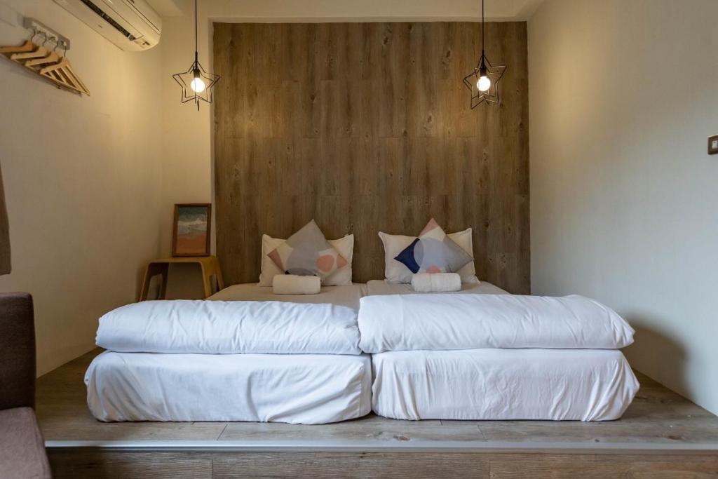 a bedroom with a bed with white sheets and pillows at Cozy House Hostel in Hualien City