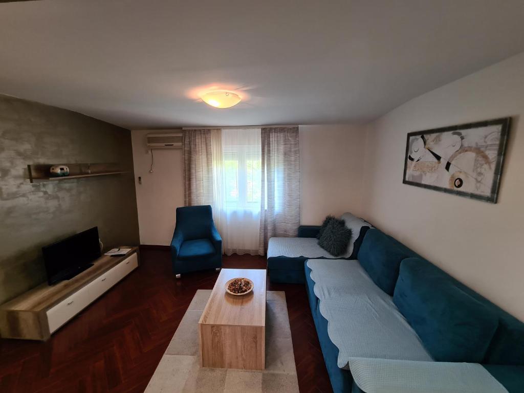 een woonkamer met een blauwe bank en een tafel bij Apolon in Novi Sad