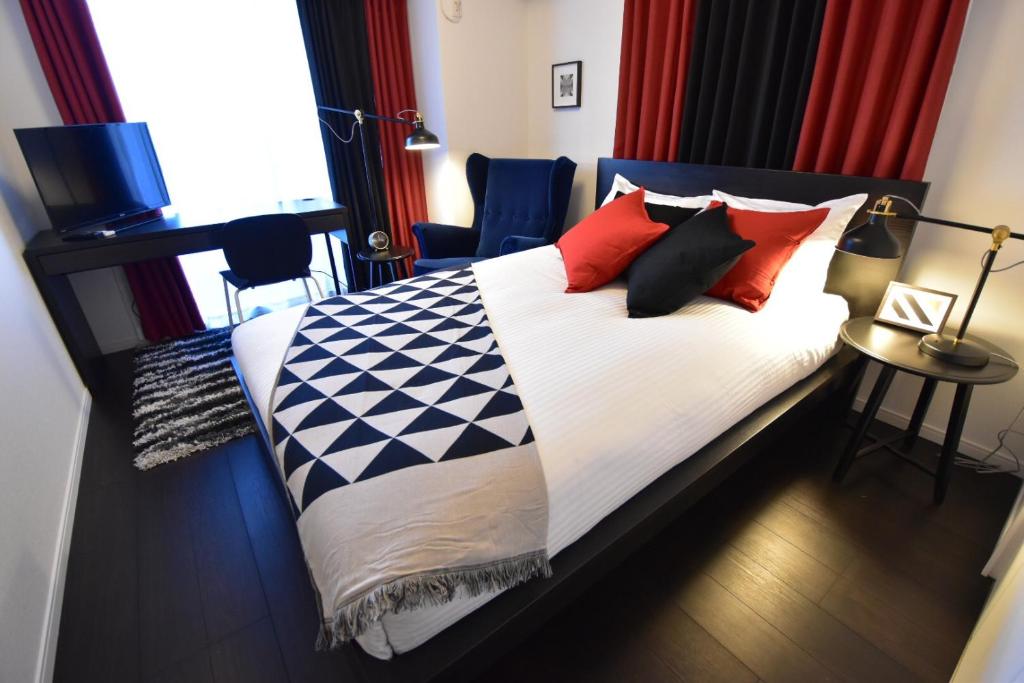 a bedroom with a bed with red and black pillows at LANG Hotel GINZA 1K with Kitchen 從東銀座站步行3分鐘 帶廚房 हिगाशी गिन्ज़ा स्टेशन से 3 मिनट की पैदल दूरी पर रसोई के साथ in Tokyo