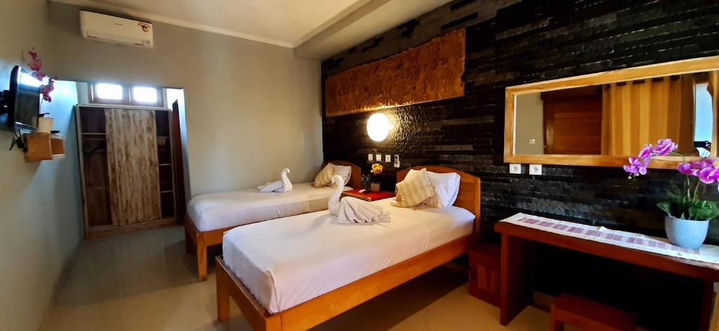 a bedroom with two beds and a desk and a window at The point surfcamp Bali in Pulukan