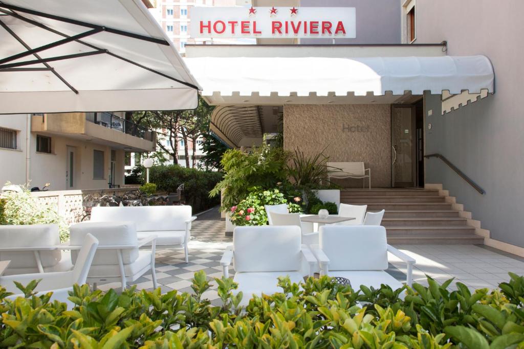 una fila de sillas y mesas blancas fuera de un hotel en Hotel Riviera, en Lido di Jesolo