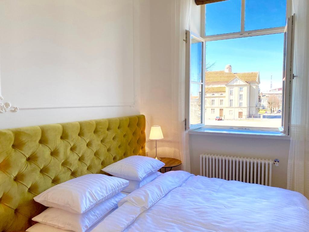 a bedroom with a bed with a yellow headboard and a window at Glamour apartment in Liepāja