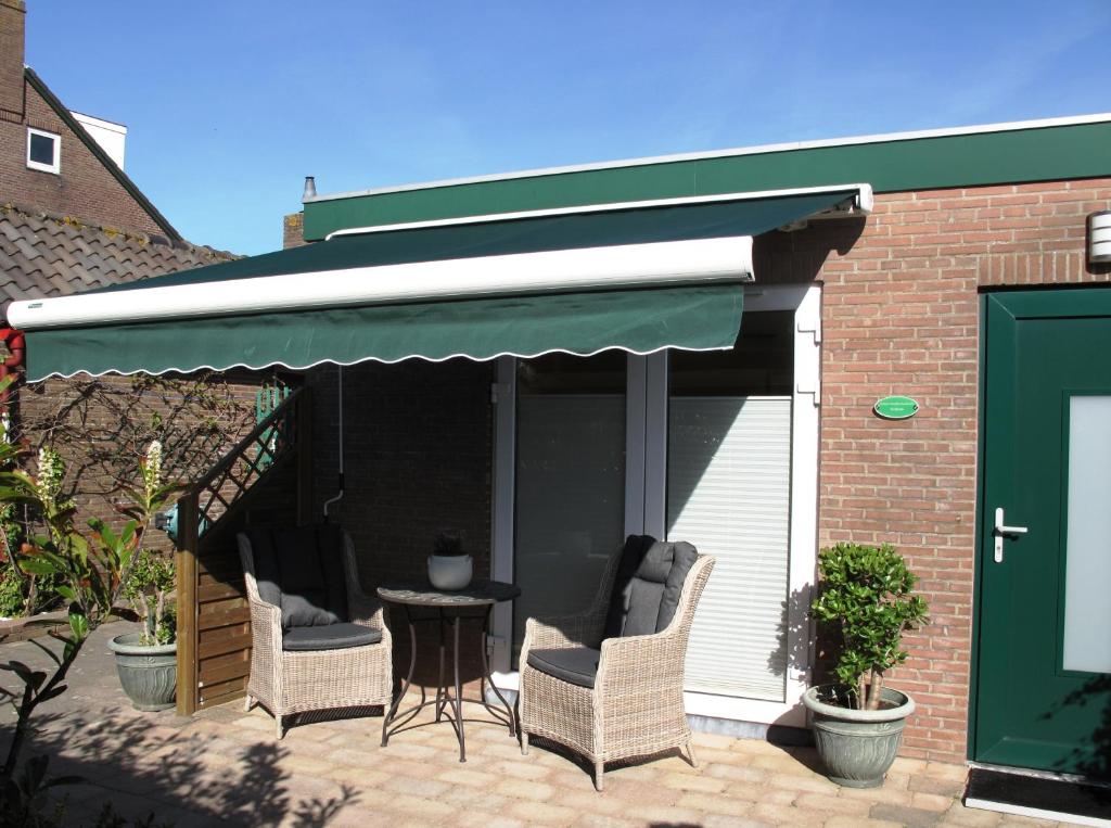 a patio with two chairs and a green awning at Duinen Paradijs Zandvoort in Zandvoort