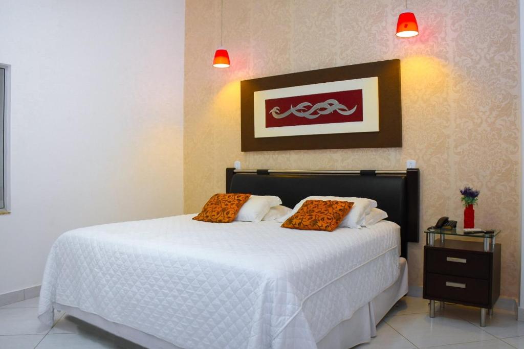 ein Schlafzimmer mit einem Bett mit orangefarbenen Kissen darauf in der Unterkunft Pioneiro Hotel in Teixeira de Freitas